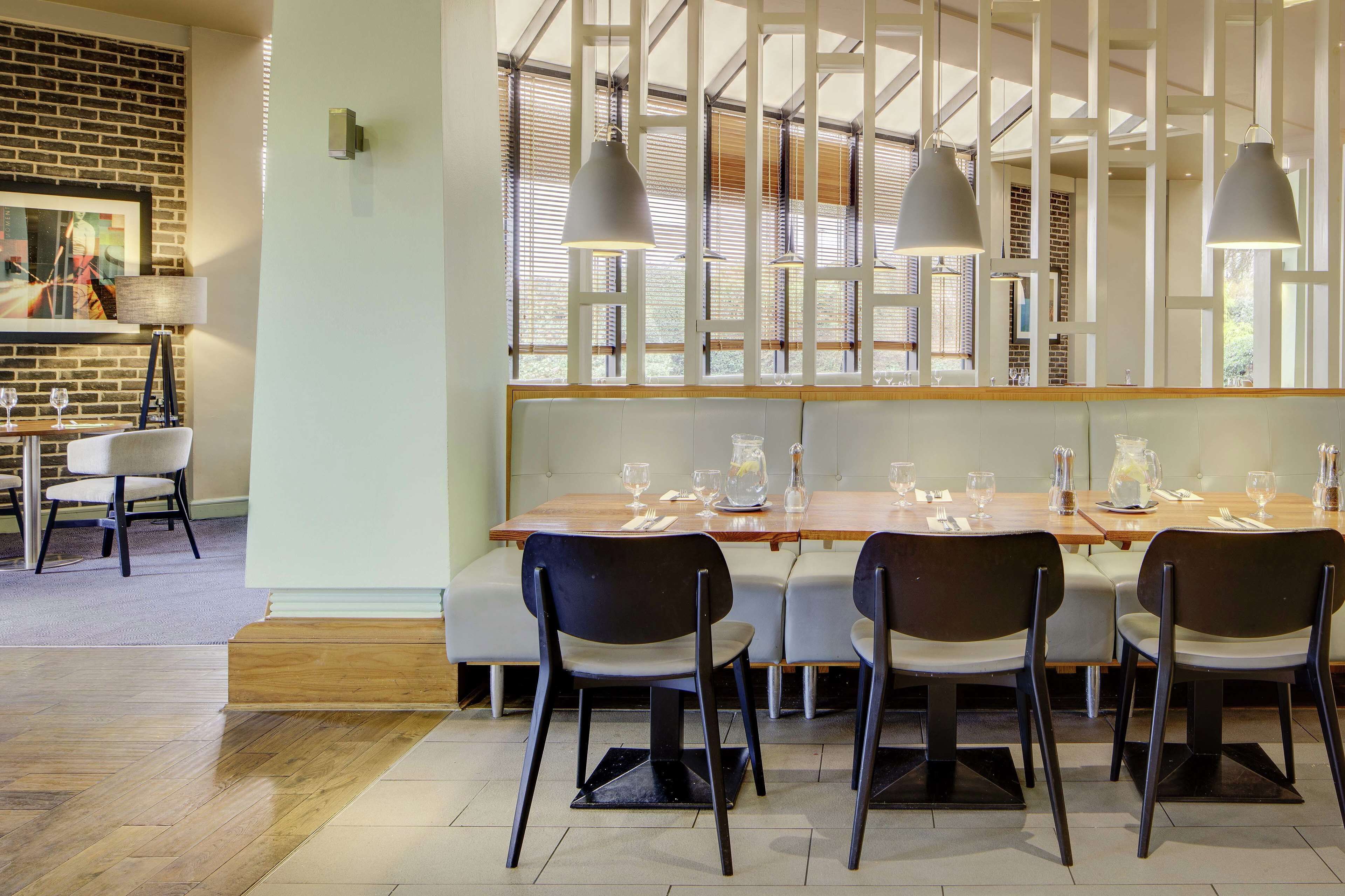 Un restaurante con mesa de madera para cuatro, sillas negras e iluminación colgante.