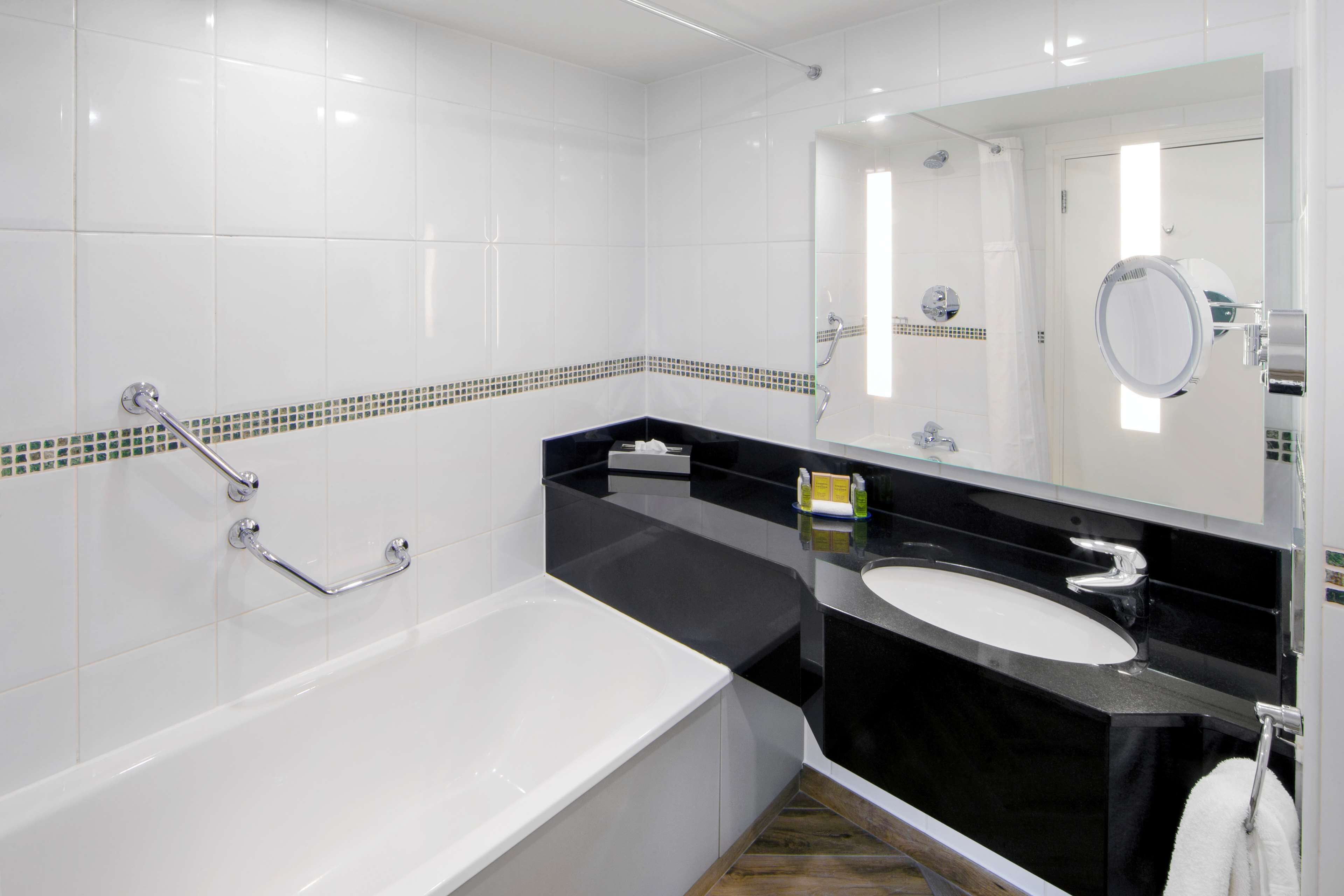 A modern bathroom with a bathtub, a black sink, and a mirror.