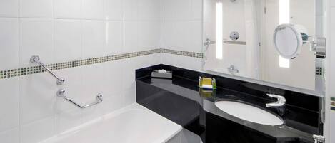 A modern bathroom with a bathtub, a black sink, and a mirror.