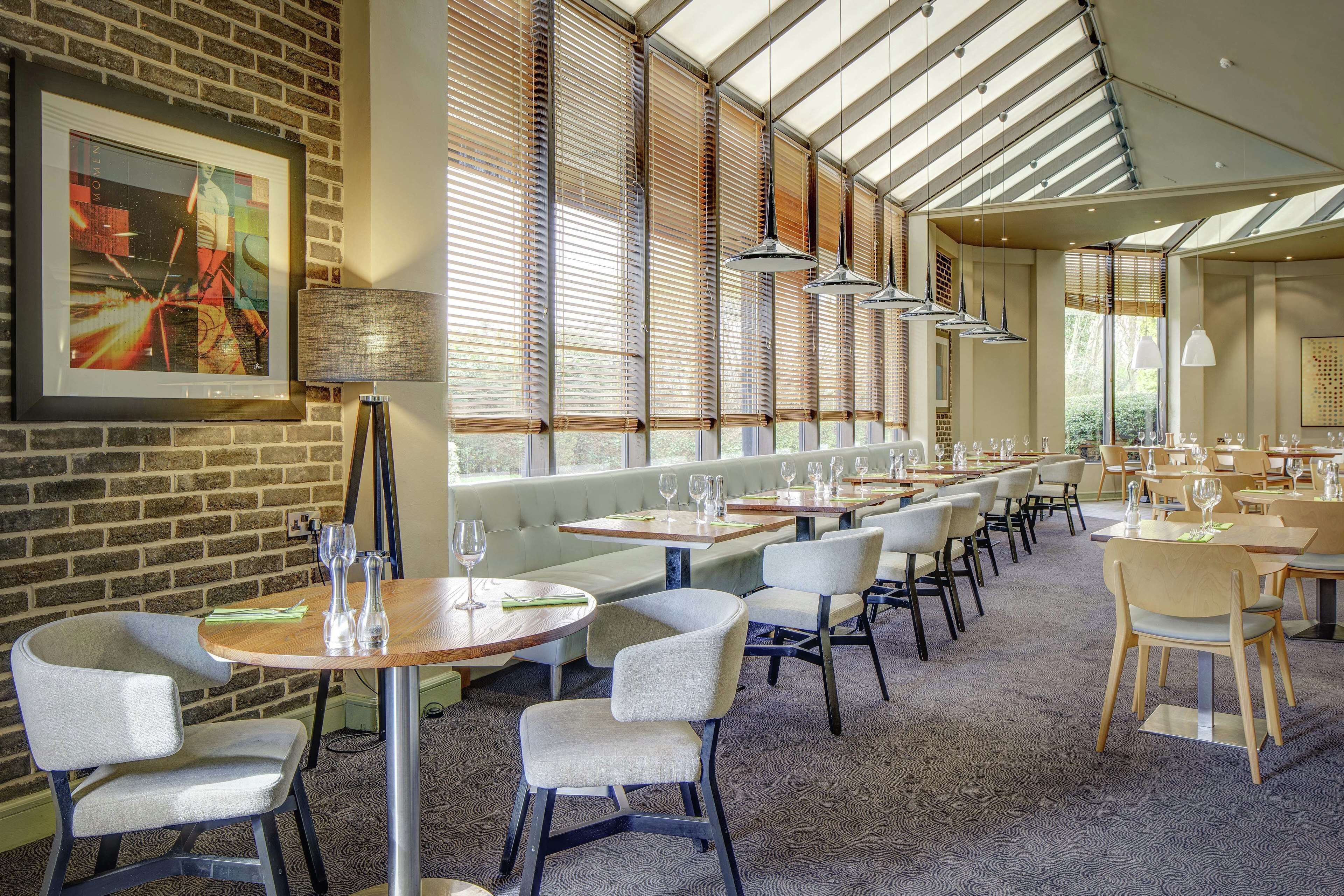 A restaurant with a brick wall, large windows, and modern furniture.