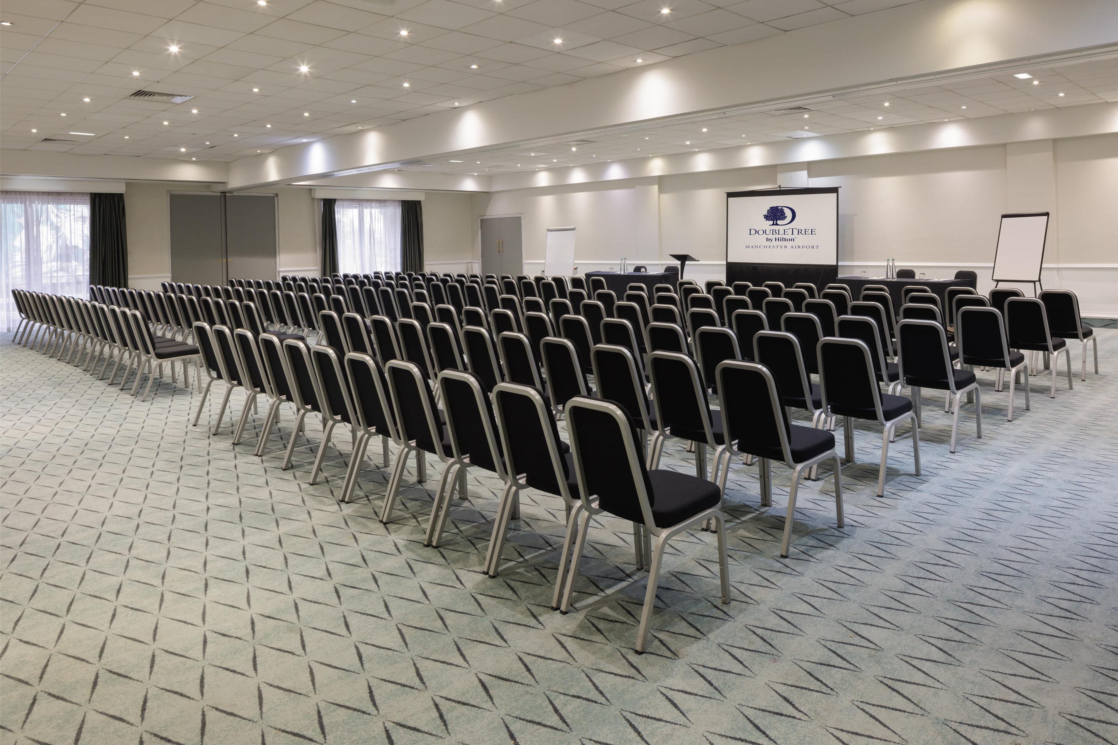 A conference room with rows of chairs, a podium, and a screen.
