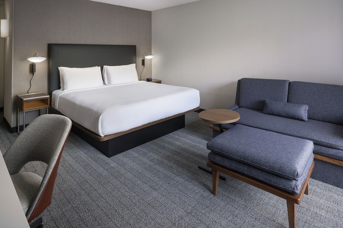Une chambre d’hôtel avec un grand lit, un canapé, un fauteuil et une petite table.