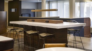 Una cocina moderna con una isla central, taburetes de bar y una cafetera.