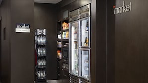 Un área de venta con un refrigerador y una estantería llena de agua embotellada y refrigerios.