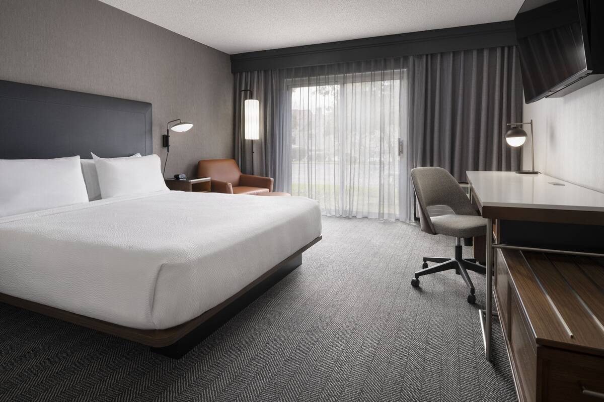 Una habitación de hotel con una cama grande, un escritorio, una silla y un televisor.