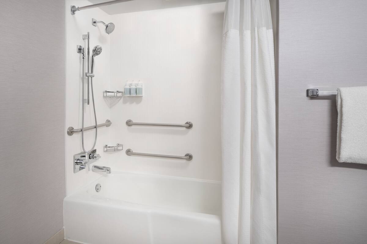 Un baño moderno con bañera, ducha y barras de apoyo.