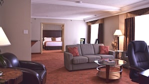 Een hotelkamer met een zithoek, inclusief een bank, fauteuils, een salontafel en een bed.