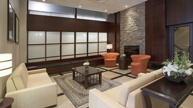 Een moderne lobby met een bank, fauteuils, een salontafel en een open haard.