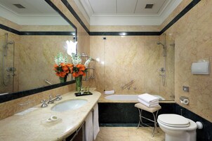 A bathroom with a double sink, a bathtub, and a toilet.