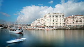 A waterfront hotel with multiple stories, a dock with boats, and a calm river. - Eurostars Hotel Excelsior (Naples)