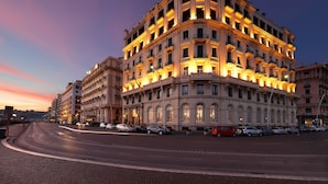 A multi-story hotel with a classic architectural style, featuring balconies and large windows. - Eurostars Hotel Excelsior (Naples)