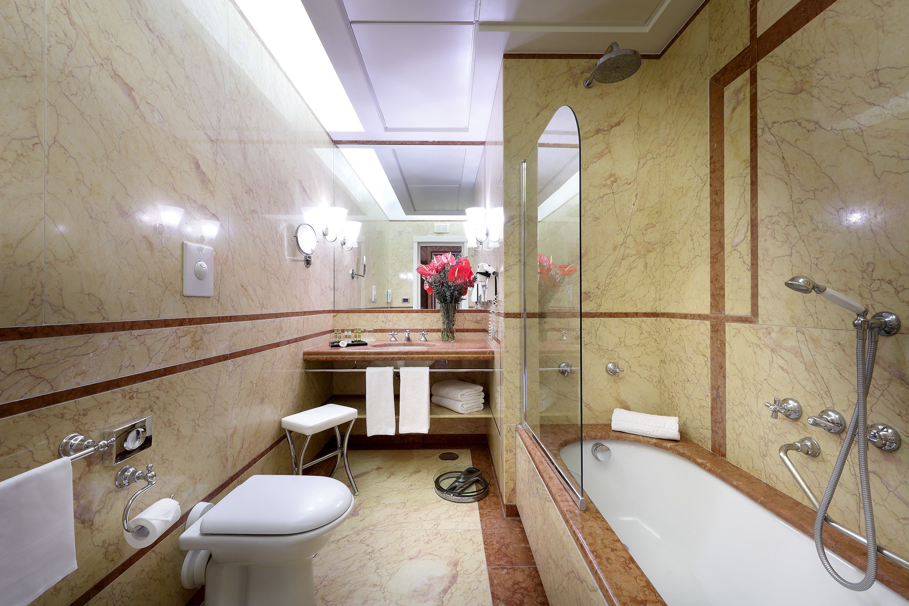 Une salle de bain avec un sol en marbre, des toilettes, un lavabo avec un miroir, une douche et une baignoire.