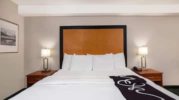 A hotel room with a large bed, two bedside tables with lamps, a framed picture on the wall, and a decorative runner on the bed.