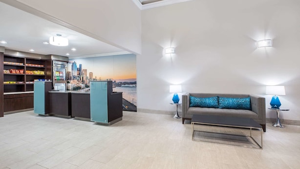 A hotel lobby with a reception desk, a sofa, and a wall mural. - La Quinta Inn by Wyndham Everett (Everett)