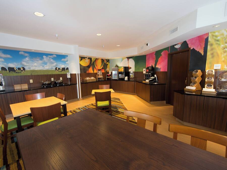 Um hall de hotel moderno com área de estar central, estação de café e balcão com cardápio.