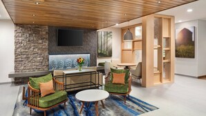 Una sala moderna con pared de piedra, televisor de pantalla plana, chimenea y zona de comedor con una mesa redonda y sillas.