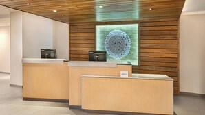 Un mostrador de recepción con una pared de paneles de madera y una pieza decorativa circular encima.