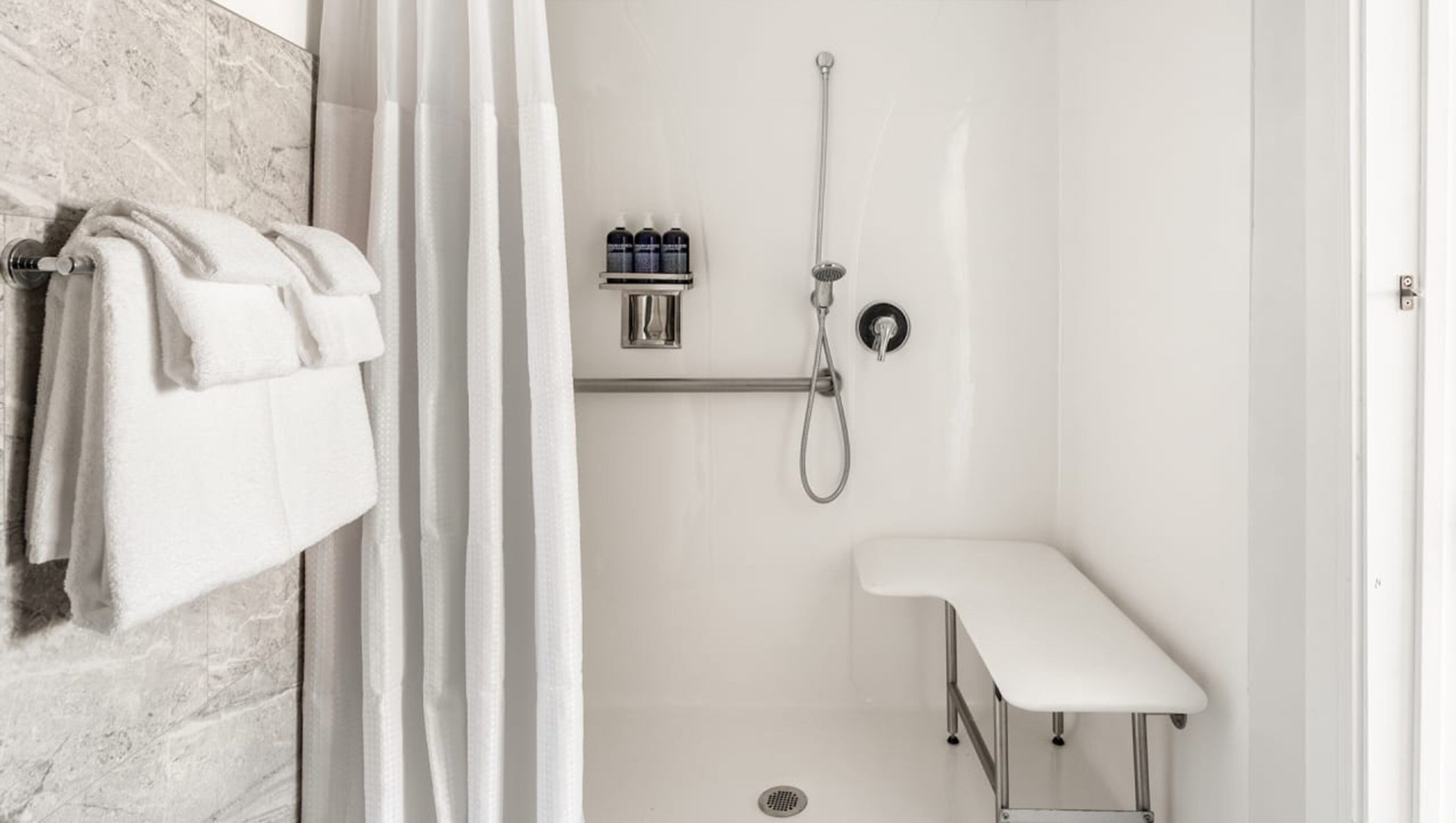 A modern bathroom with a shower, a white sink, and a towel rack with towels.