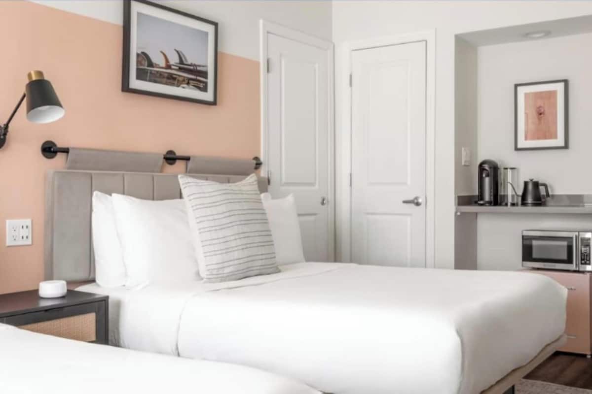 Une chambre d’hôtel équipée d’un lit, d’une lampe de chevet et d’une kitchenette avec un four à micro-ondes.