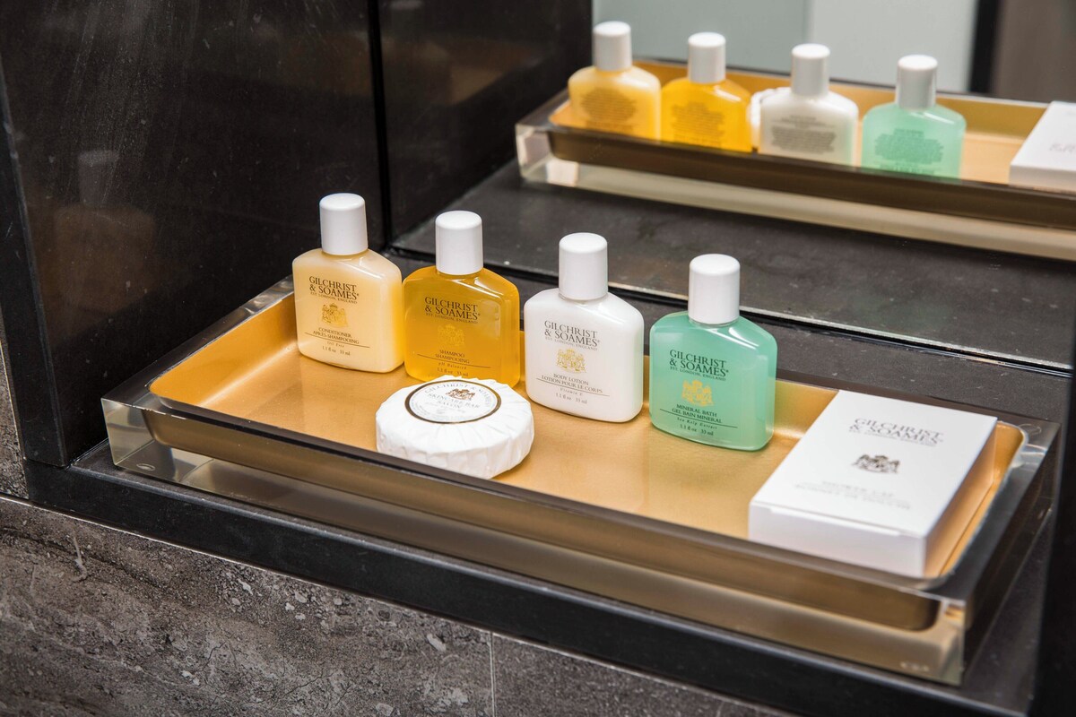 A tray with various Gilchrist & Soames toiletries including shampoo, body lotion, and a mineral bath gel.