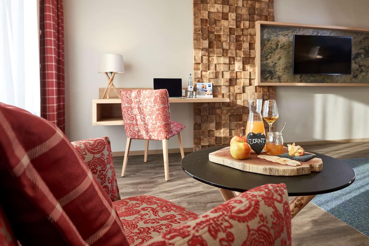 Un salon moderne avec une table basse ronde, un canapé rouge à motifs, un meuble TV en bois et un téléviseur fixé au mur.