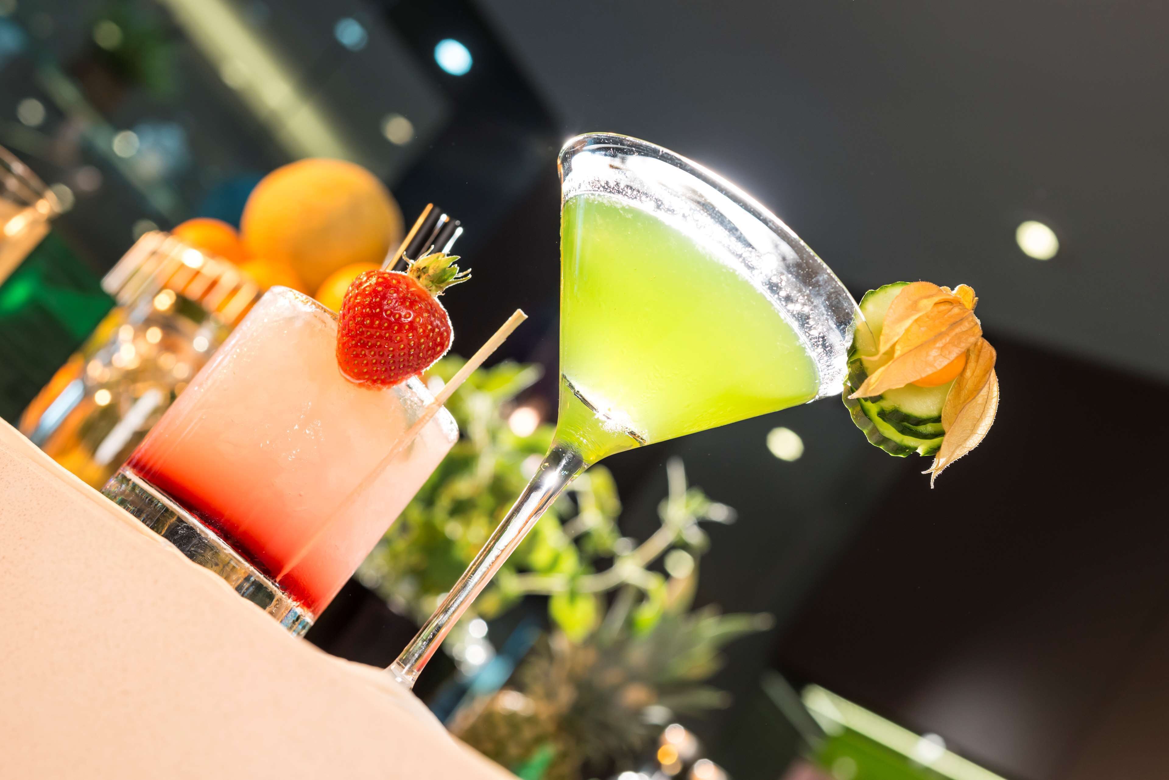 A bar area with a variety of drinks, including a martini and a cocktail with a strawberry garnish.