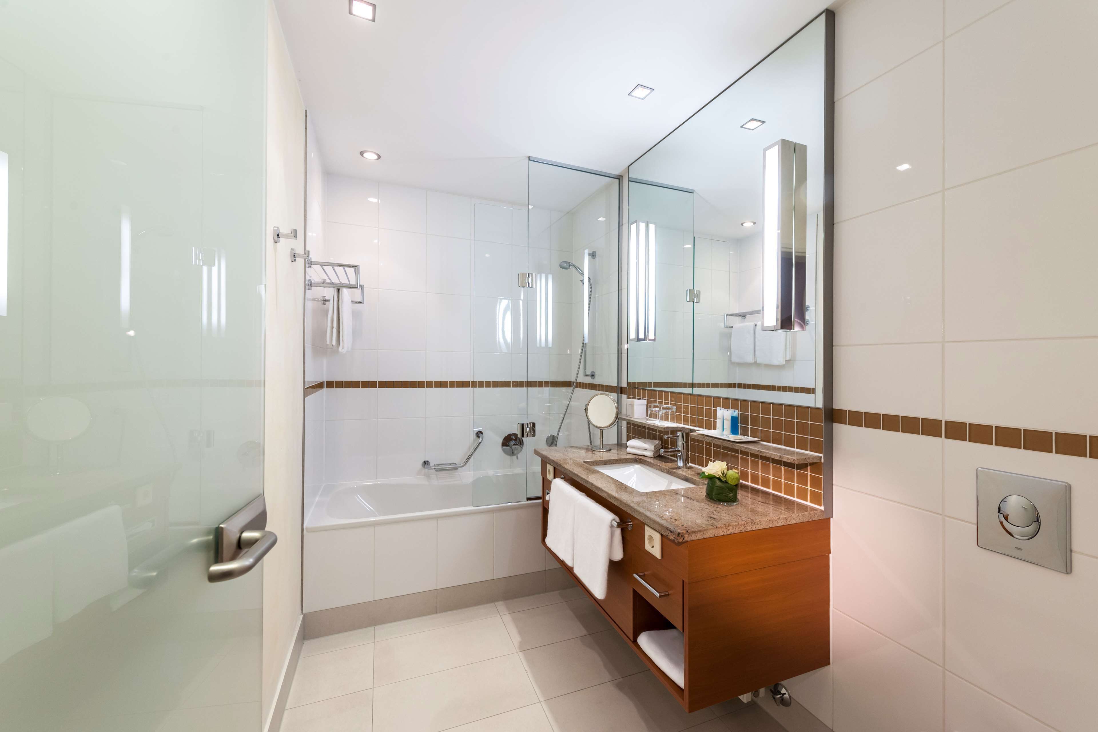 Ein modernes Badezimmer mit Duschkabine aus Glas, einer Badewanne, einem Waschtisch mit Spiegel und einem Handtuchhalter.