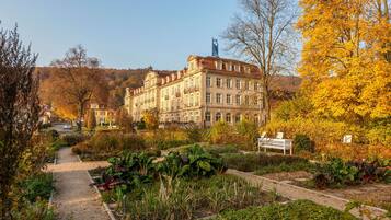 A large, historic building with a garden pathway leading to a bench.