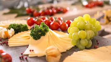 A cheese board with various cheeses, grapes, and cherry tomatoes.