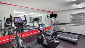 A gym with various exercise machines, a mirrored wall, and a red stripe along the floor. - Ramada by Wyndham Bowling Green (Bowling Green)