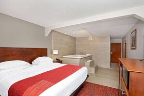 A hotel room with a large bed, a separate bathroom with a bathtub, and a small desk.