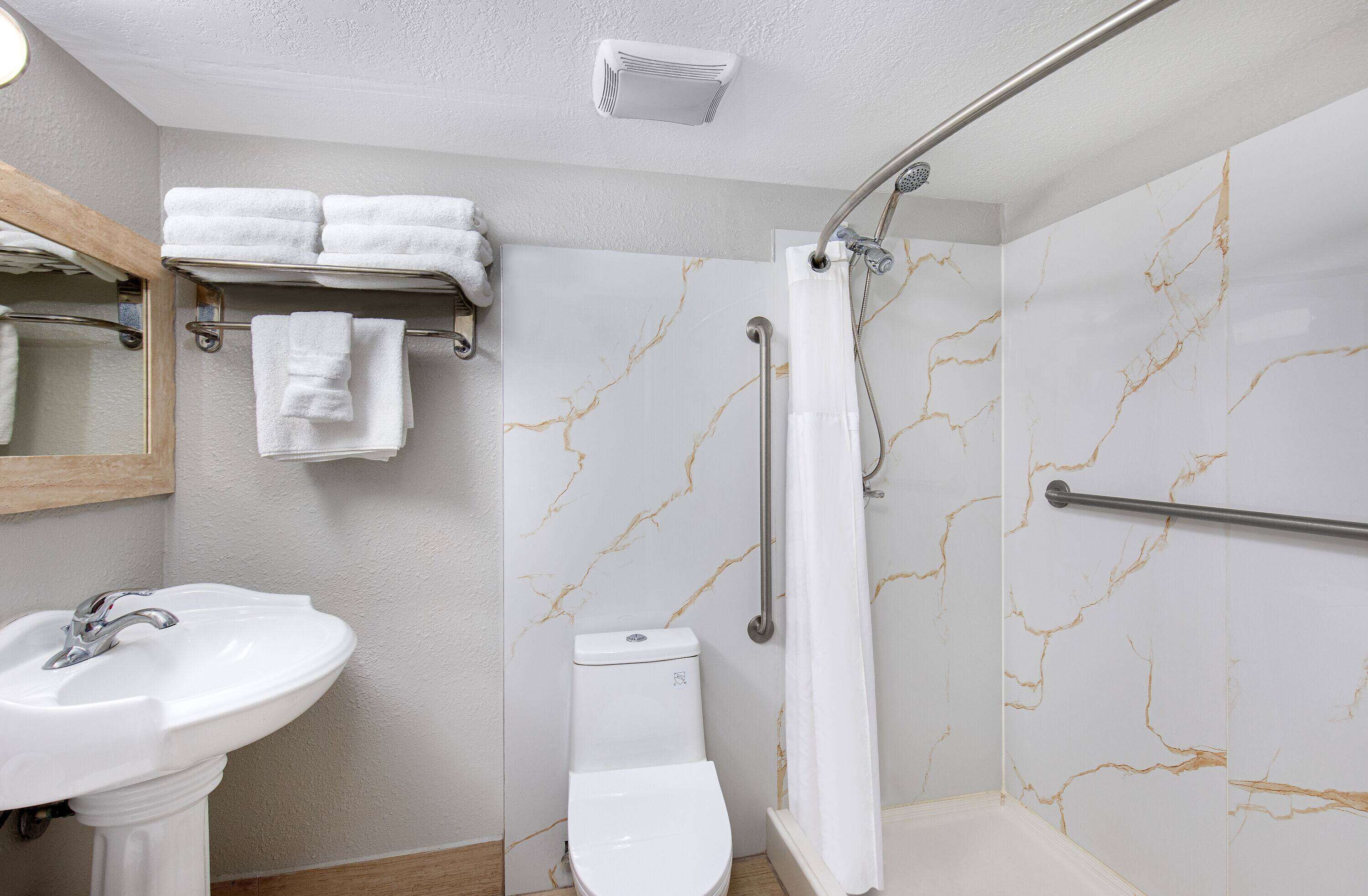 Ein Badezimmer mit weißem Waschbecken, Toilette und Dusche mit Marmorwänden.