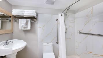 A bathroom with a white sink, toilet, and shower with marble walls.