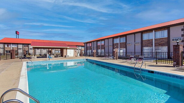 A swimming pool with a red-roofed building in the background. - Ramada by Wyndham Bowling Green (Bowling Green)