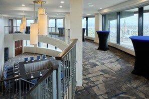 A modern hotel lobby with a curved staircase, a conference table, and a panoramic city view. - Ottawa Marriott Hotel (Ottawa)