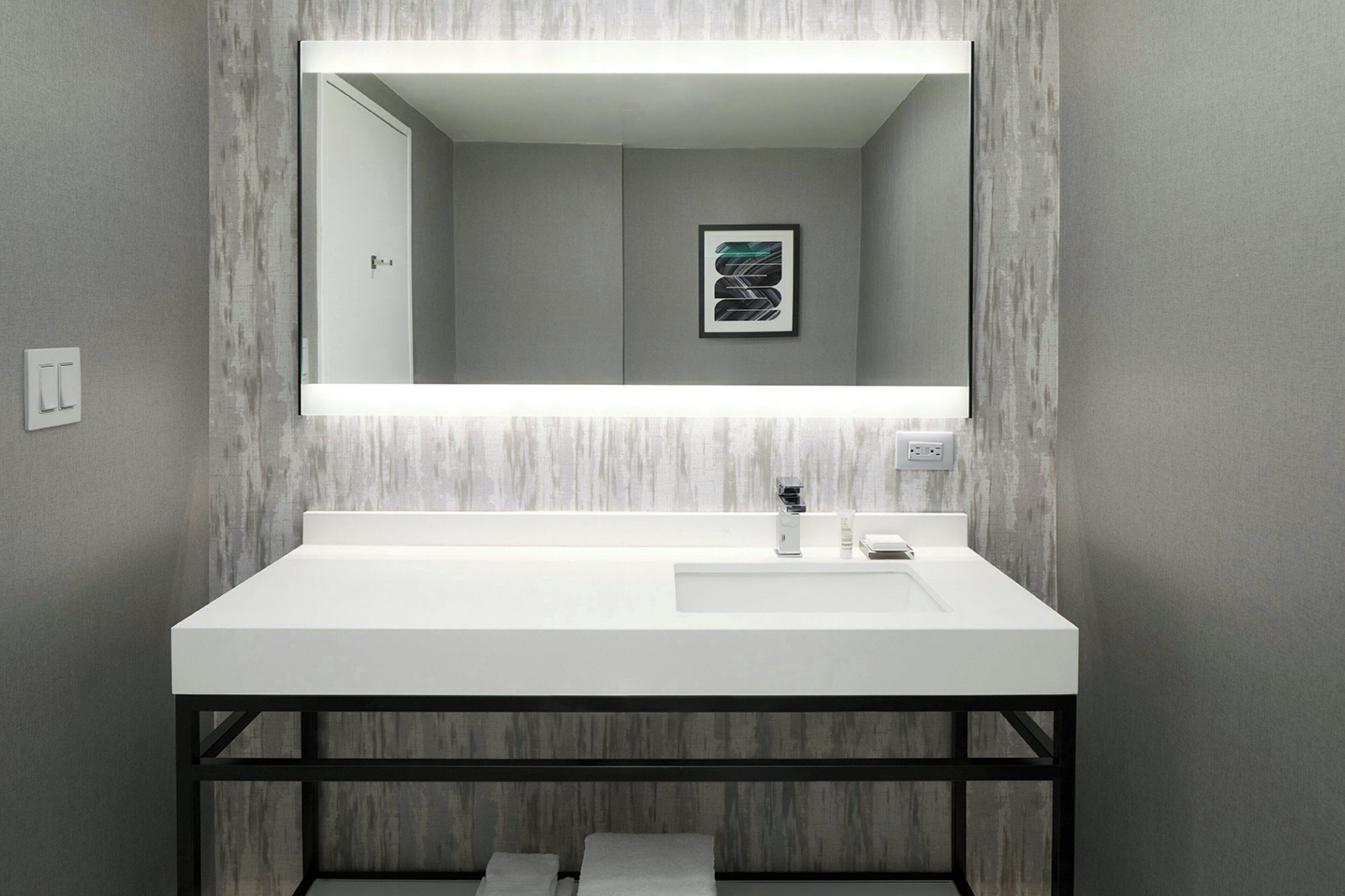 A modern bathroom with a white sink, black frame, and a large mirror.