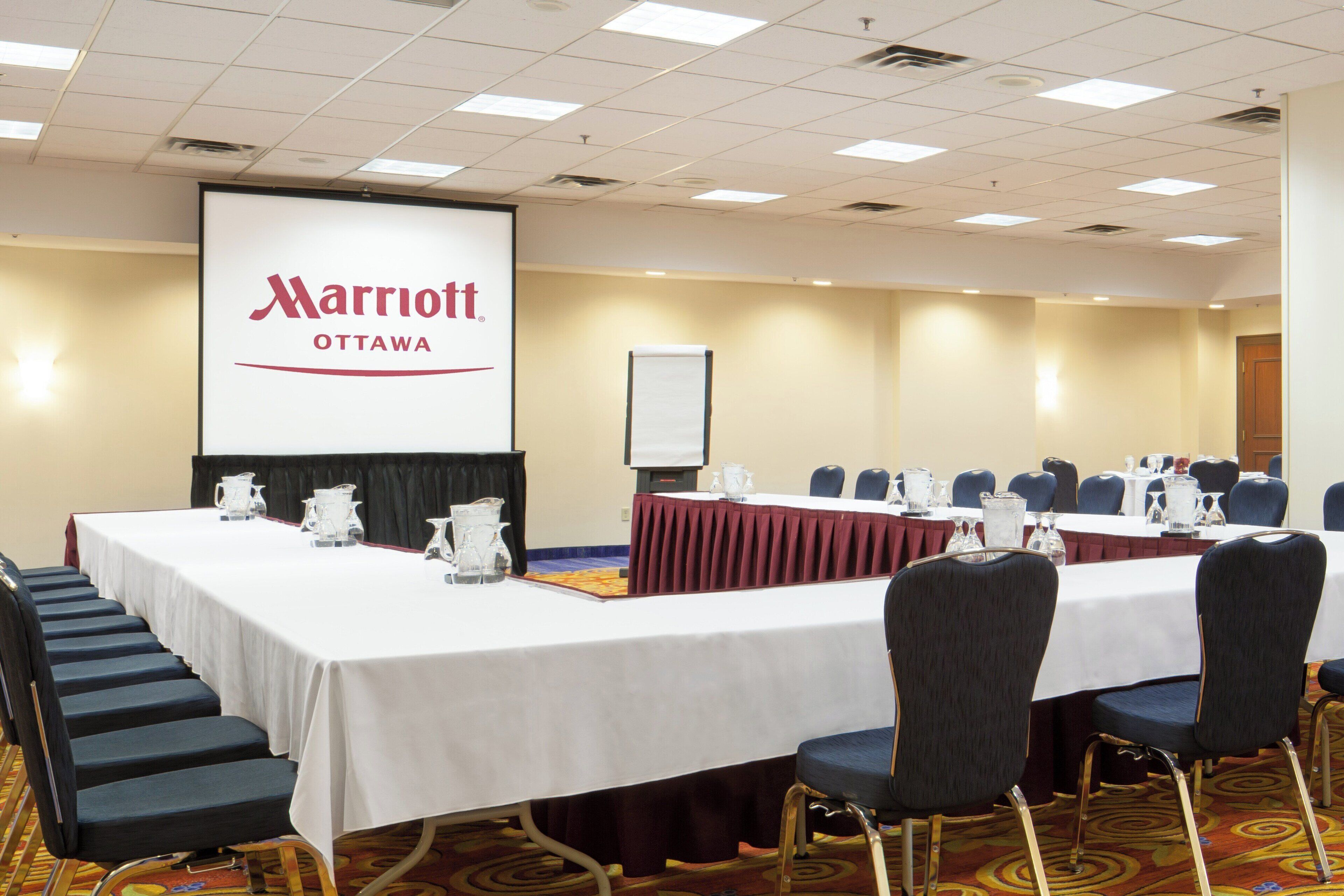 Une salle de conférence avec une longue table, des chaises et un écran affichant le texte « Marriott Ottawa ».
