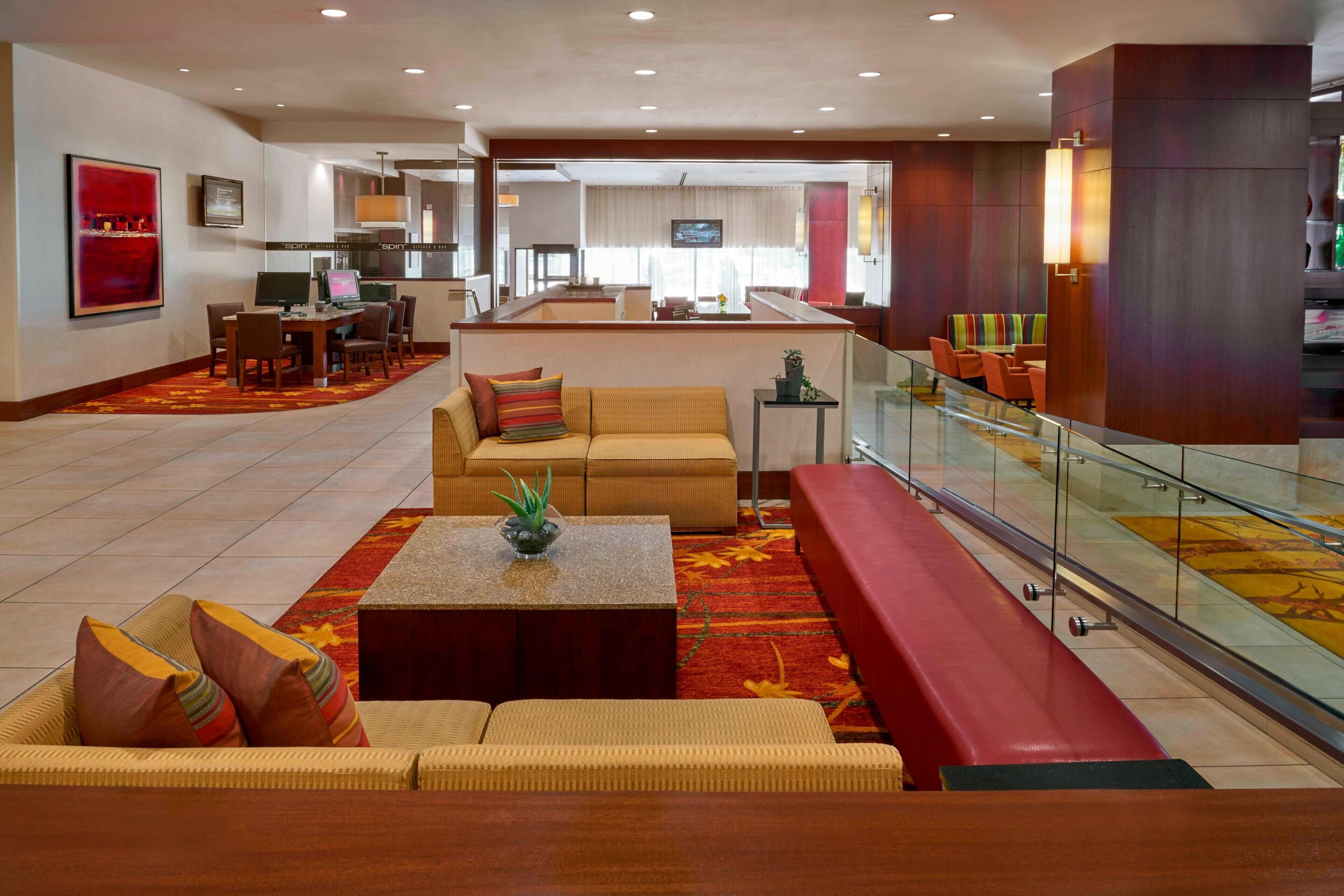 A hotel lobby with a seating area, a dining table, and a TV screen.