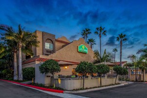 Un hotel con un letrero que dice "LAQUINTA INN & Suites" y un patio con mobiliario exterior.