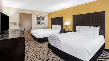Une chambre d’hôtel avec deux lits, un bureau, une télévision et une porte.