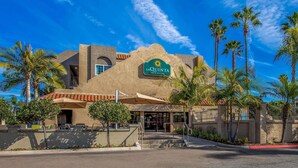 A hotel with a prominent sign, palm trees, and a clear blue sky.