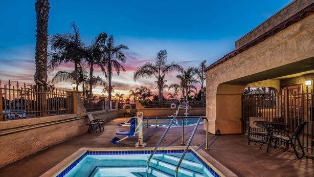 A pool area with a view of palm trees and a sunset.