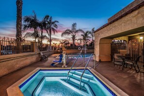 Zona de piscina con vistas a palmeras y un atardecer.
