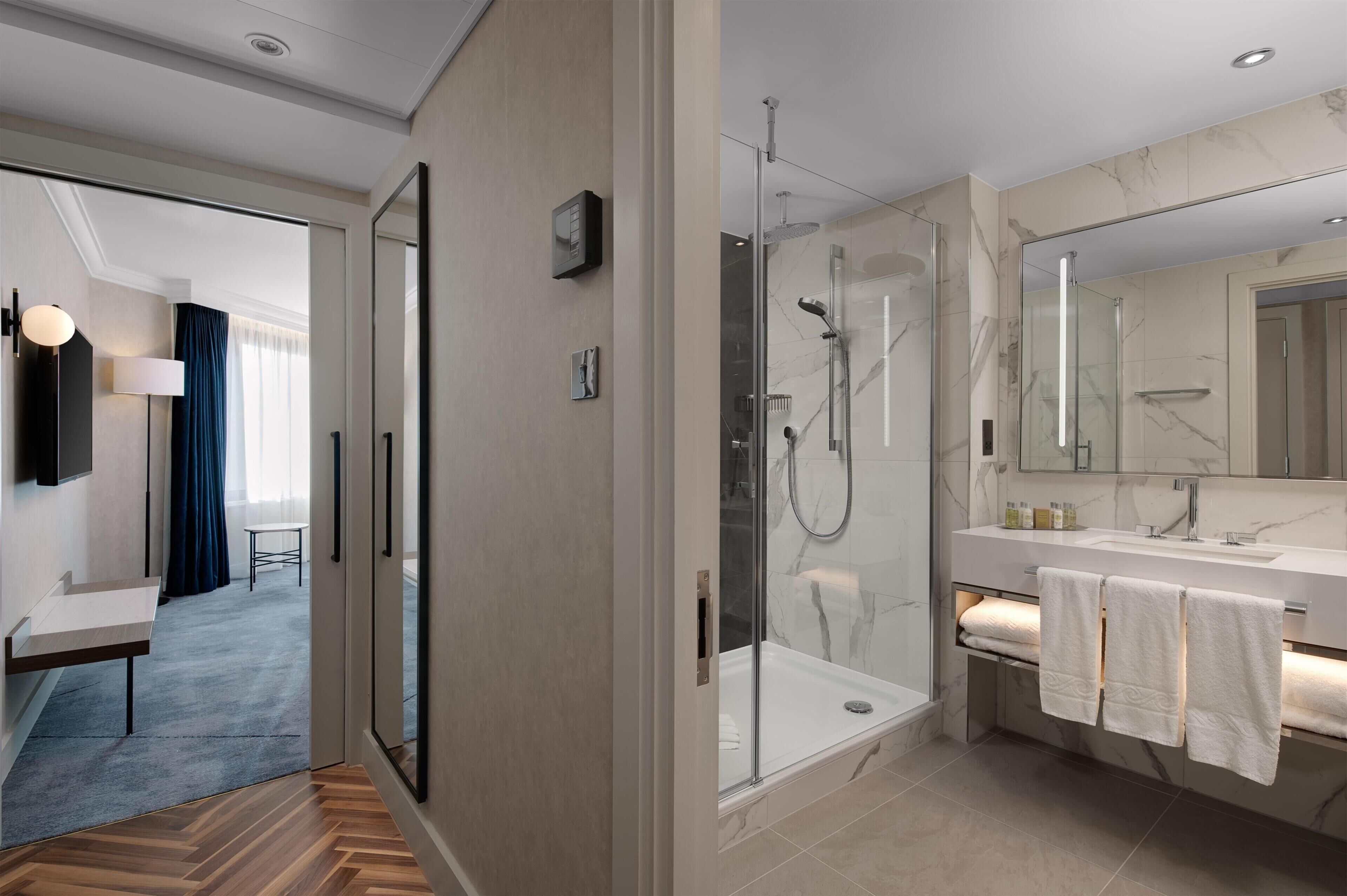 Une salle de bain moderne avec une douche à parois de verre, un grand miroir et un comptoir en marbre.
