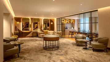 Een moderne hotellobby met een centrale zithoek, een bar en een eetruimte.