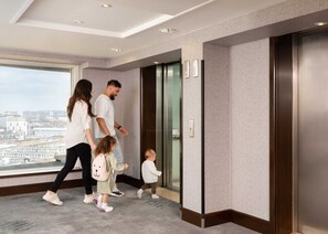 Eine Familie benutzt einen Aufzug in einem modernen Gebäude mit Blick auf die Stadt.