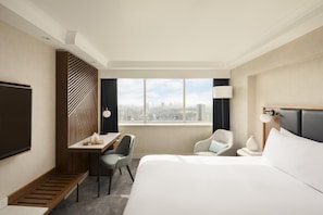 A hotel room with a bed, a desk, a chair, a TV, and a view of the cityscape. - Hilton London Metropole (London)