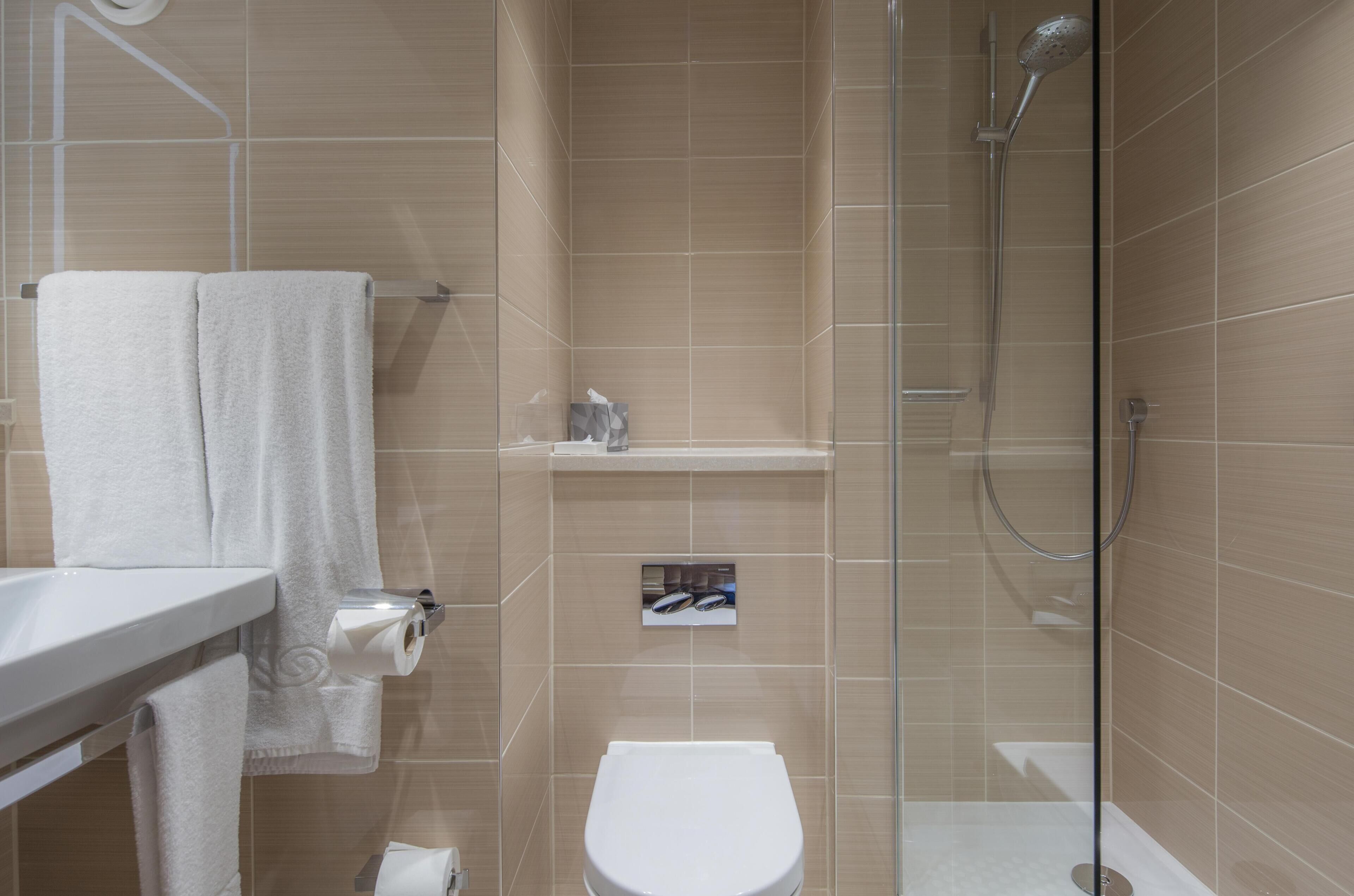A bathroom with a toilet, a shower, and a sink.