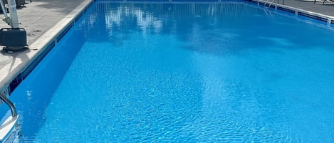 Una piscina al aire libre de temporada, sillones reclinables de piscina