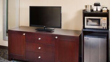 A wooden cabinet with a flat-screen TV, a microwave, and a coffee maker.